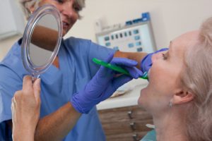 Female dental hygienist brushing the teeth of a patient