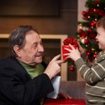 Small boy giving present to grandfather at christmas