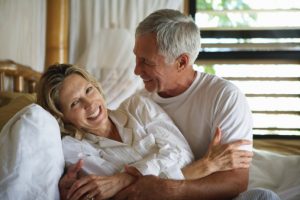Senior couple embracing in bed, smiling, close-up