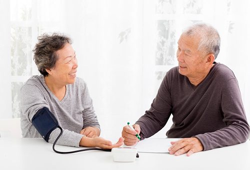 happy Senior couple taking blood pressure in living room