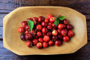 Acerola Cherry raw, fresh, in wooden trough on rustic wooden table, antioxidant fruits. Top View