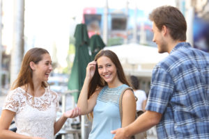Candid girl with a friend flirting with a boy in the street
