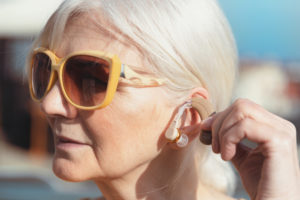 Senior woman puts on the hearing aid. Deafness, senior health care concept
