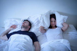 Tired and annoyed woman of her boyfriend snoring in the bed