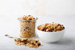 Homemade granola with coconut, raisins and almonds for breakfast in a jar and a bowl