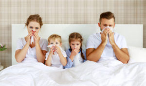 colds and viral diseases. family with runny nose and fever in bed at home
