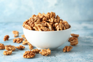 Bowl with tasty walnuts on color table