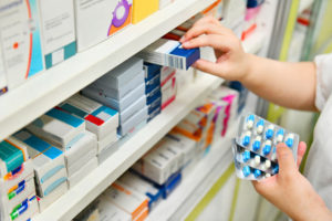 Pharmacist holding medicine box and capsule pack in pharmacy drugstore.