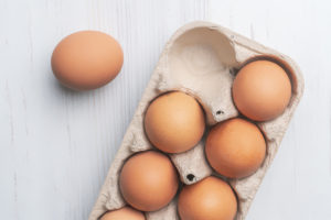 fresh eggs in paper tray on white surface