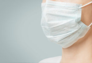 Unrecognizable woman in medical protective mask against virus and infection diseases, close-up. Copy-space in left part of image.