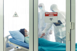 Doctor examines corona or covid-19 virus patient in the clean room with covid 19 and restricted area sign in front of the room