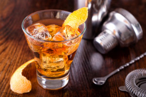 A delicious old fashioned cocktail on a wooden bar counter top.