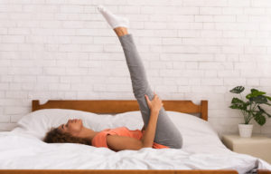Morning workout in bedroom. Woman doing yoga exercise on bed at home