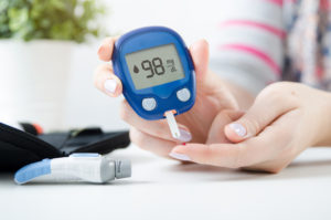Diabetes checking blood sugar level. Woman using lancelet and glucometer at home.