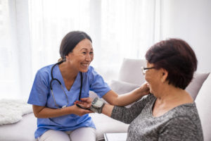 Portrait of young Asian nurse with elderly woman. Helpful volunteer taking care of senior lady at healthcare home. Picture of a senior lady with her friendly caregiver.