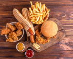 Delicious but unhealthy food with ketchup and mustard on vintage cutting board. Fast carbohydrates, junk and fast food. Warm wooden background.