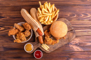 Delicious but unhealthy food with ketchup and mustard on vintage cutting board. Fast carbohydrates, junk and fast food. Warm wooden background.