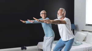Portrait of happy senior couple performing exercise at home. Two positive couple full of energy and optimism in old age. Copy space image