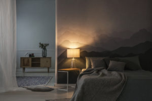 Bedroom interior in the night with warm light of lamp on table near wooden cupboard