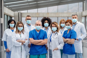 A group of doctors with face masks looking at camera, corona virus concept.