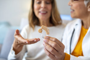 Modern hearing aids.The choice of hearing aid in the doctor's office. Doctor showing hearing aid. Otolaryngologist giving hearing aid to patient. The hearing aid for a senior woman