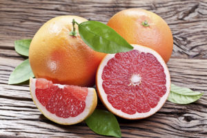 Grapefruits with leaves on a wooden table.