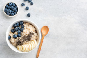 Healthy Breakfast Oatmeal Bowl With Banana, Blueberry And Chia Seeds In Bowl On Grey Concrete Background. Top View Copy Space