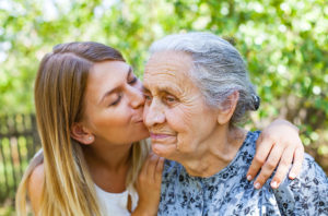 Young woman kissing her old grandmother in the park