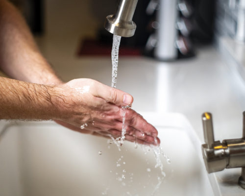 Close up of hands being washed in sink
