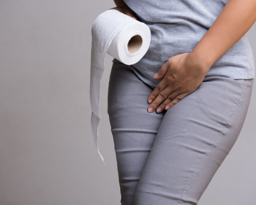 Woman hand holding her crotch lower abdomen and tissue or toilet paper roll. Disorder, Diarrhea, incontinence. Healthcare concept.