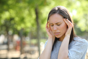Woman suffering migraine outdoors in a park