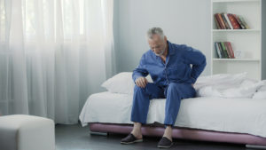 Retired man sitting in bed and feeling terrible pain in back, health and illness, stock footage