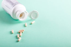 Pills, tablets and bottle on turquoise background. Copy space
