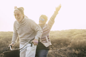 Happiness and freedom concept no limit age with old aged couple laughing smiling and having lot of fun together on a bike in outdoor leisure activity - youthful and playful people retired