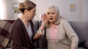 Old deaf woman listening senior friend, hearing disease, old age health care