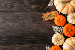 Happy Thanksgiving tag with fall side border of pumpkins and leaves on a dark wood background with copy space