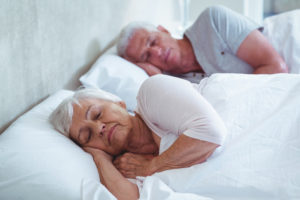 Senior couple sleeping on bed at home