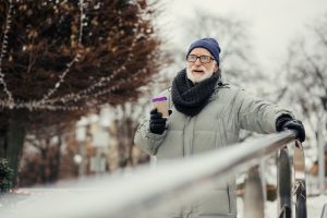 Calm bearded walking alone in the park in winter and holding a carton cup of hot chocolate