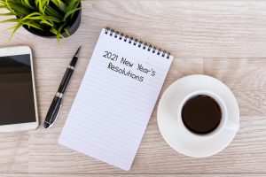 2021 New Year's Resolutions text on note pad with smart phone and cup of coffee