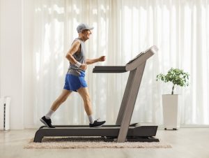 Full length profile shot of an active senior man on a treadmill in a luxurious home