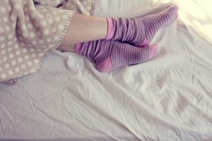 girl with pink striped socks, sleeping in bed