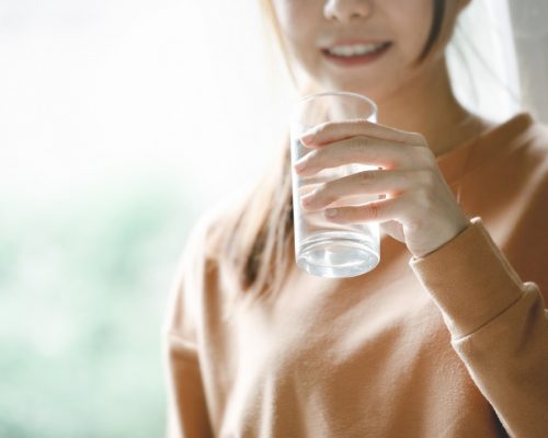 Happy woman drinking water while smiling, copy space.