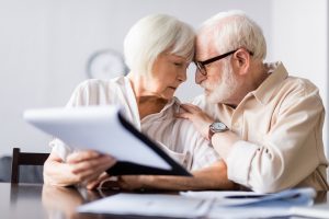 Selective focus of man embracing senior wife near documents on table