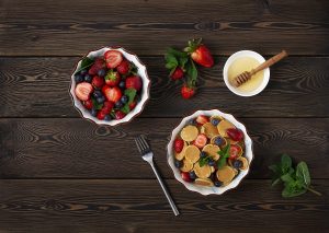 food Dutch mini pancakes, homemade, with strawberries and blueberries, breakfast , on a wooden table, top view, no people, horizontal,