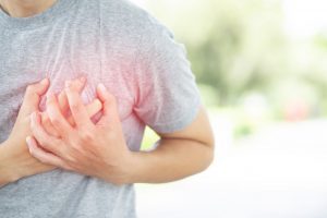 Both hands grasp the left chest of a person with chest pain.