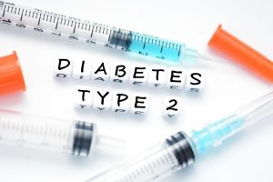 Type 2 diabetes text spelled with plastic letter beads placed next to an insulin syringe