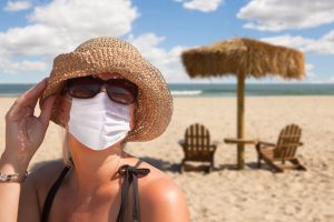 Vacationing Woman Wearing Face Mask on Sandy Beach..