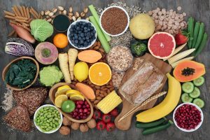 High fibre super food with whole grain bread loaf and rolls, fruit, vegetables, whole wheat pasta, cereals, seeds and nuts. Foods omega 3, anthocyanins, antioxidants and vitamins. Top view.