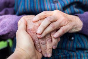 Close up picture of elderly disabled female hands with loving caregiver