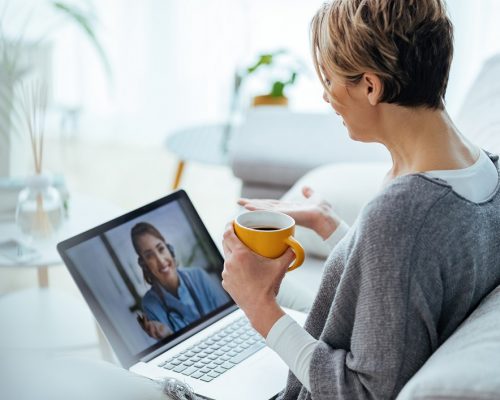 Woman sitting on the sofa while making video call over laptop with her doctor.